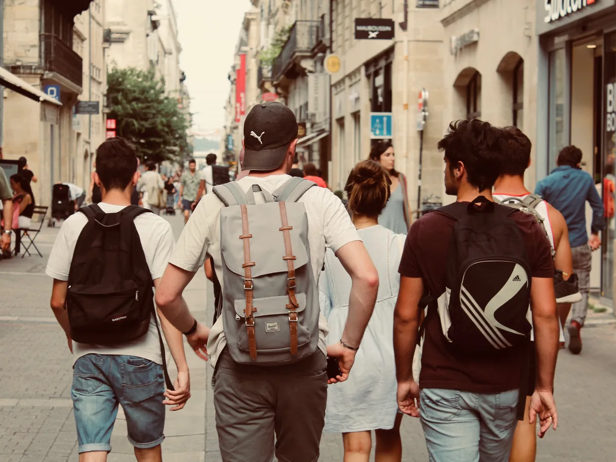 Friends with backpacks walking together down a busy old-town street
